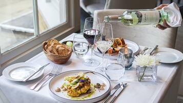 Una mesa de comedor dispuesta con platos, cubiertos, vasos y una botella de vino blanco frío Lanya.