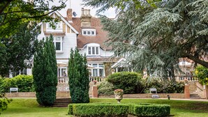 A large, traditional house with a well-maintained garden, including a hedge and a flower bed. - Rowhill Grange Hotel & Utopia Spa (Dartford)