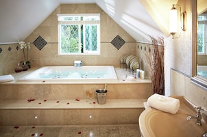 Un baño con una bañera grande, un lavabo y una ventana.