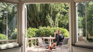 A conservatory with a table and chairs, surrounded by lush greenery. - Rowhill Grange Hotel & Utopia Spa (Dartford)