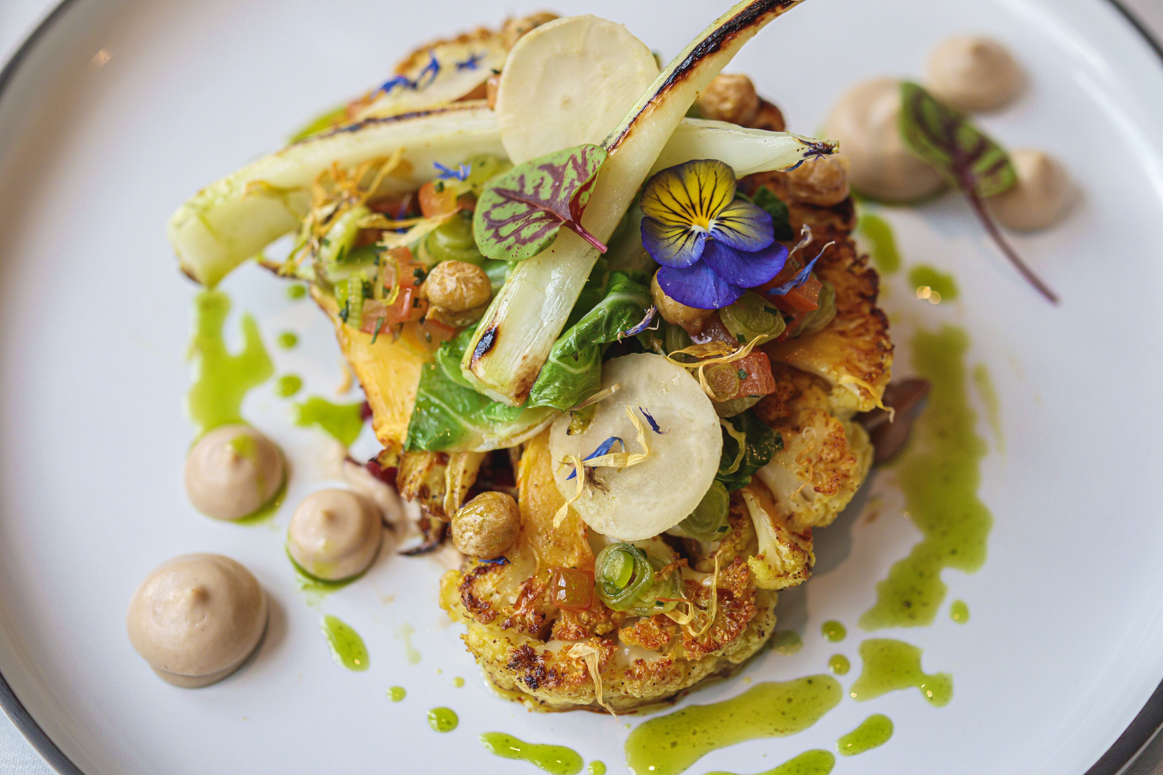 A plated dish with various vegetables and garnishes.