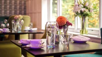 Una mesa de comedor con un florero, una jarra de vidrio y un florero morado.