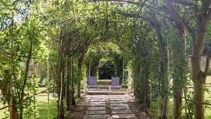 A stone pathway leading through a garden with a pergola overhead. - Rowhill Grange Hotel & Utopia Spa (Dartford)