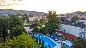 A residential area with a swimming pool, houses, and a hilly landscape in the background. - Krikonis Hotel (Ioannina)