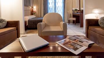 Una habitación de hotel con una cama, una silla, un escritorio, una laptop y una revista sobre una mesa.