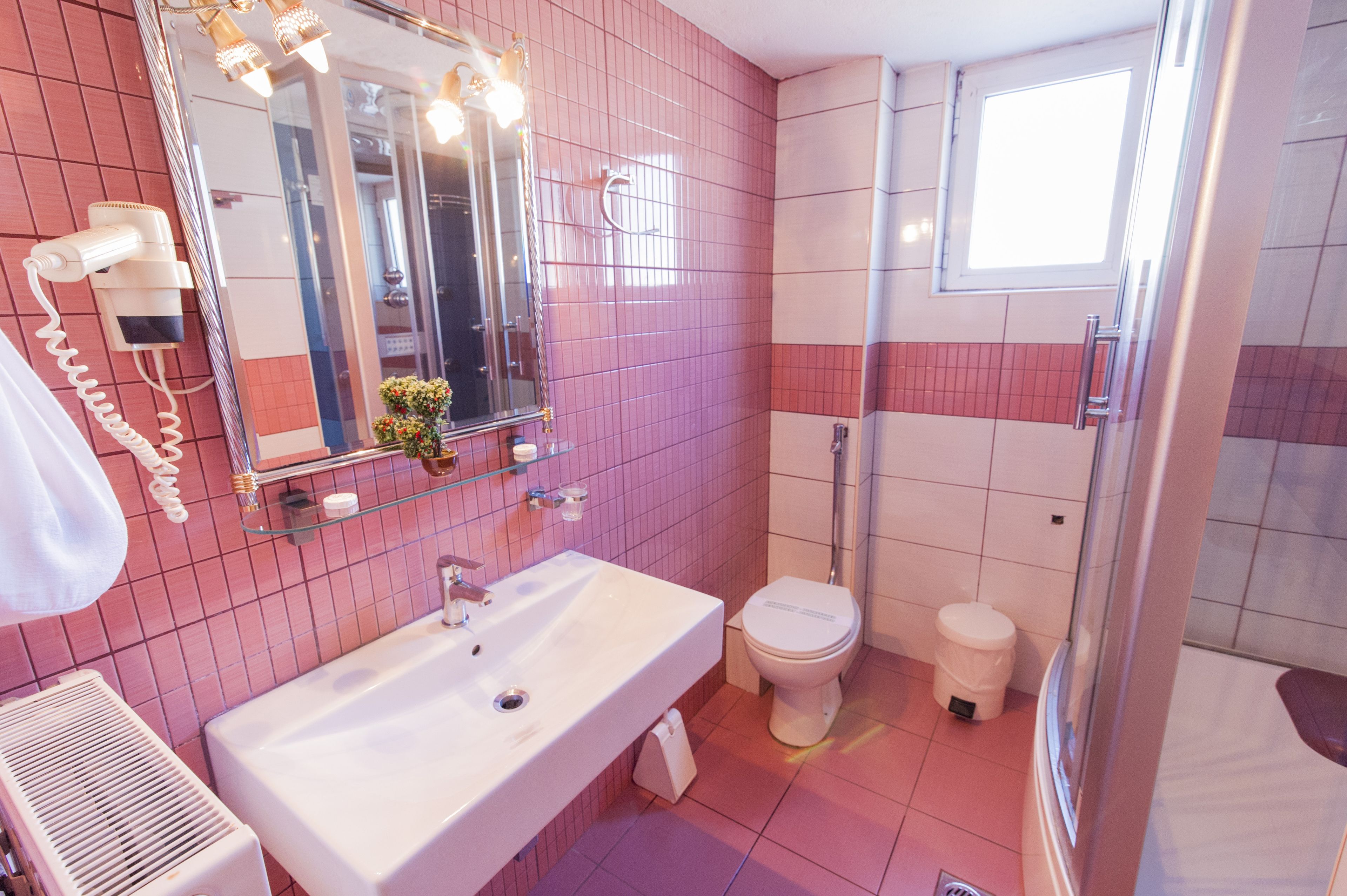 A bathroom with a white sink, a mirror with lights, a toilet, and a shower area.