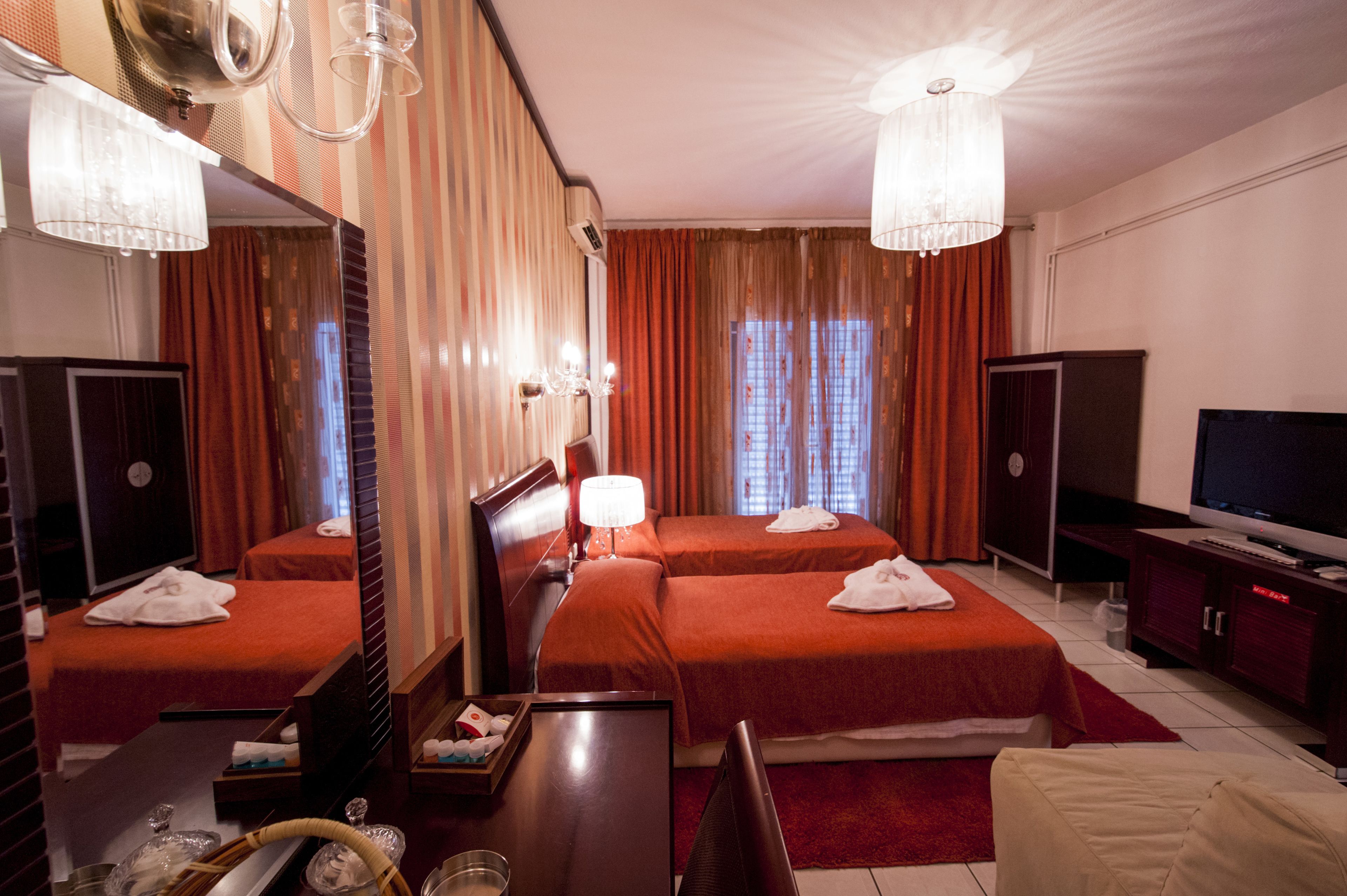 A hotel room with two beds, a TV, a desk, and a mirror.