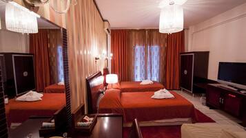 A hotel room with two beds, a TV, a desk, and a mirror.