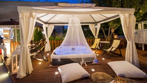A hot tub under a canopy with lounge chairs and cushions. - Krikonis Hotel (Ioannina)