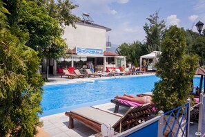 Relax by the pool surrounded by lounge chairs and umbrellas, with a bar nearby.