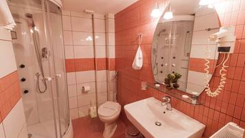 Une salle de bain avec une douche à parois de verre, des toilettes, un lavabo et un miroir.