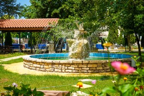 Surrounded by lush greenery, a serene fountain creates a tranquil atmosphere in this peaceful park setting.