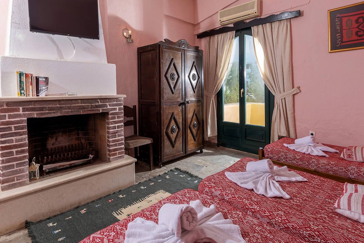 Ein Hotelzimmer mit Kamin, Kleiderschrank, einem Bett mit Handtüchern und Blick durch eine Tür.