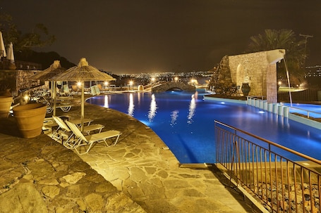 Una piscina al aire libre, sombrillas, sillones reclinables de piscina