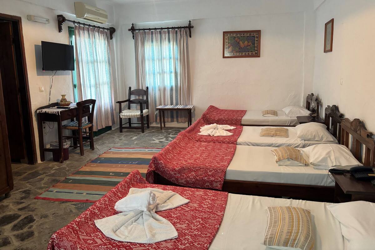 Ein Hotelzimmer mit zwei Betten, einem Schreibtisch, einem Stuhl und einem Fernseher.