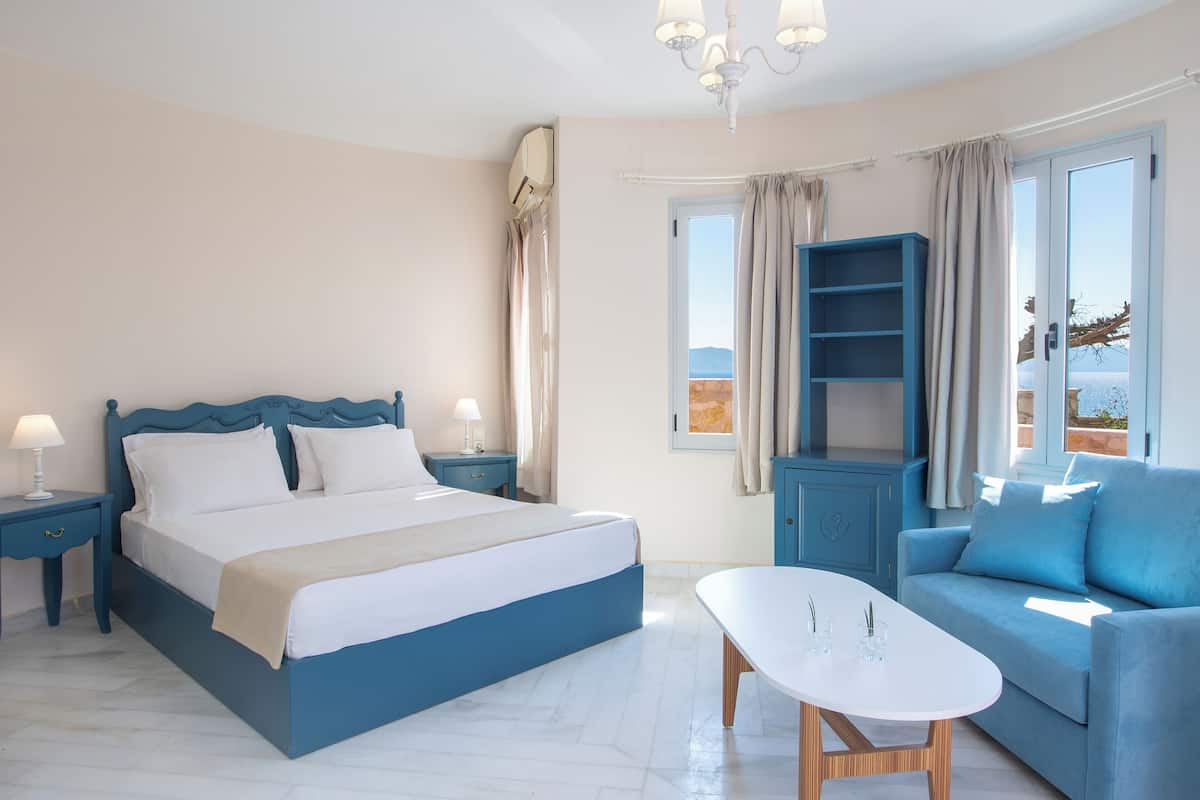 A bedroom with a bed, bedside tables, a sofa, and a table.