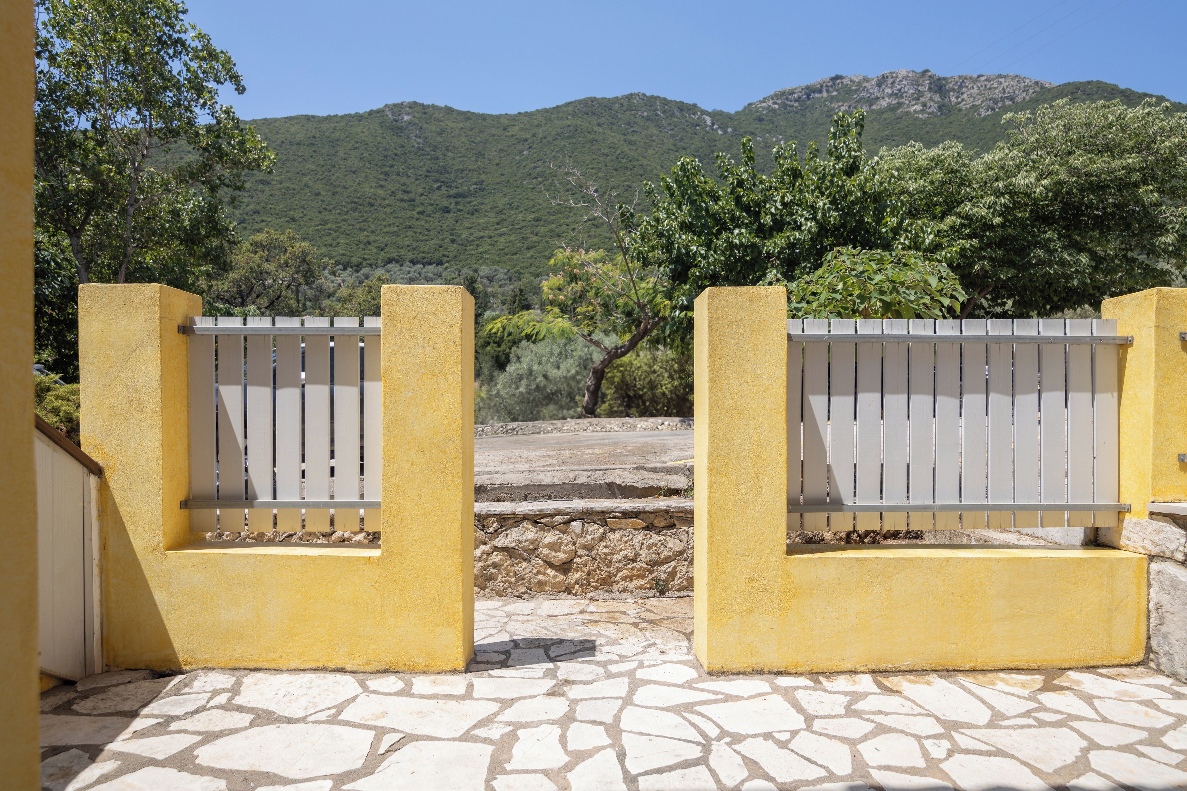 A yellow gate with a stone pathway leading to a mountainous landscape.