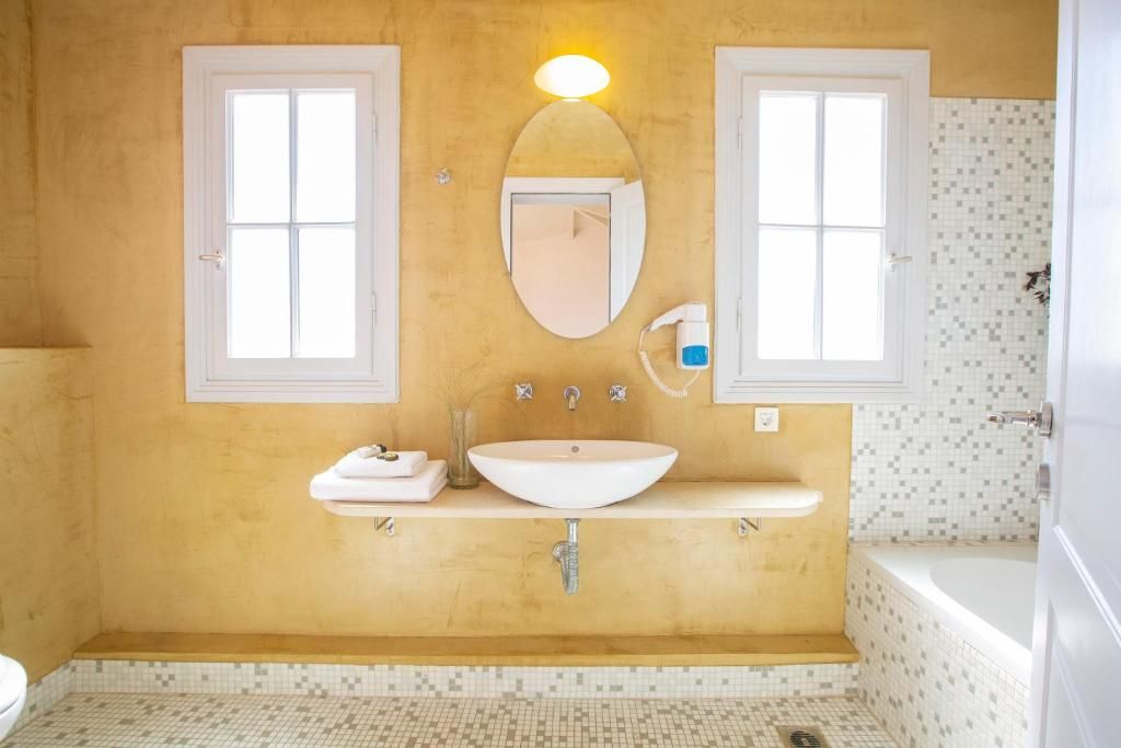 A bathroom with a white sink, two mirrors, a towel rack, and a shower area.