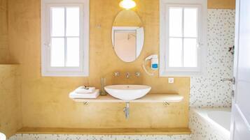 A bathroom with a white sink, two mirrors, a towel rack, and a shower area.