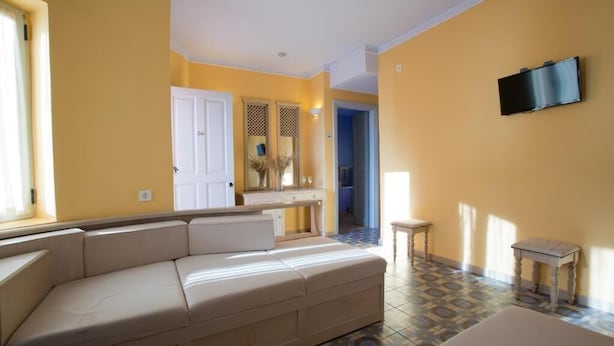 Una sala de estar con un sofá color beige, una mesita y un televisor montado en la pared.