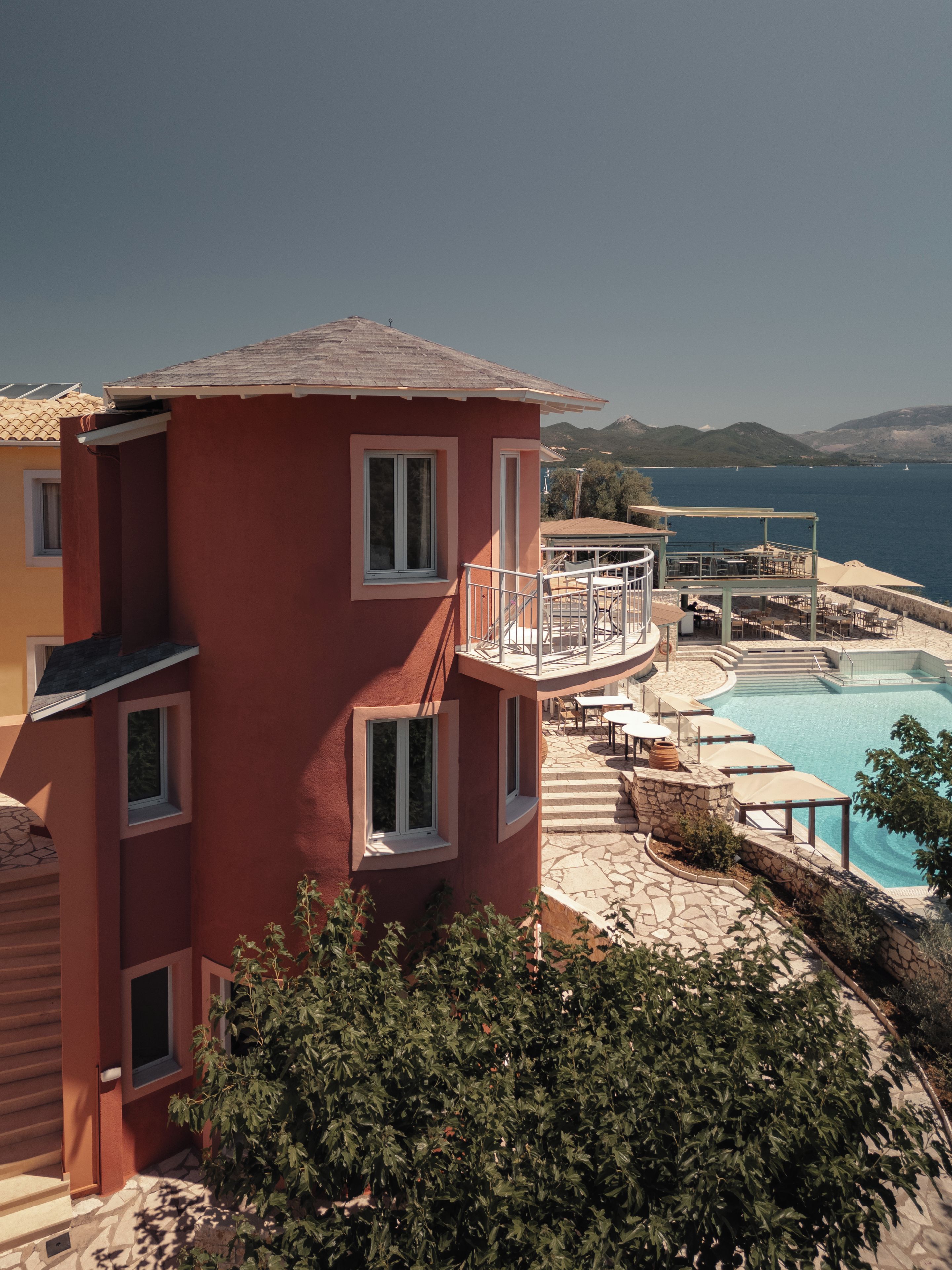 A multi-story building with a pool area, including a sun terrace and outdoor seating.