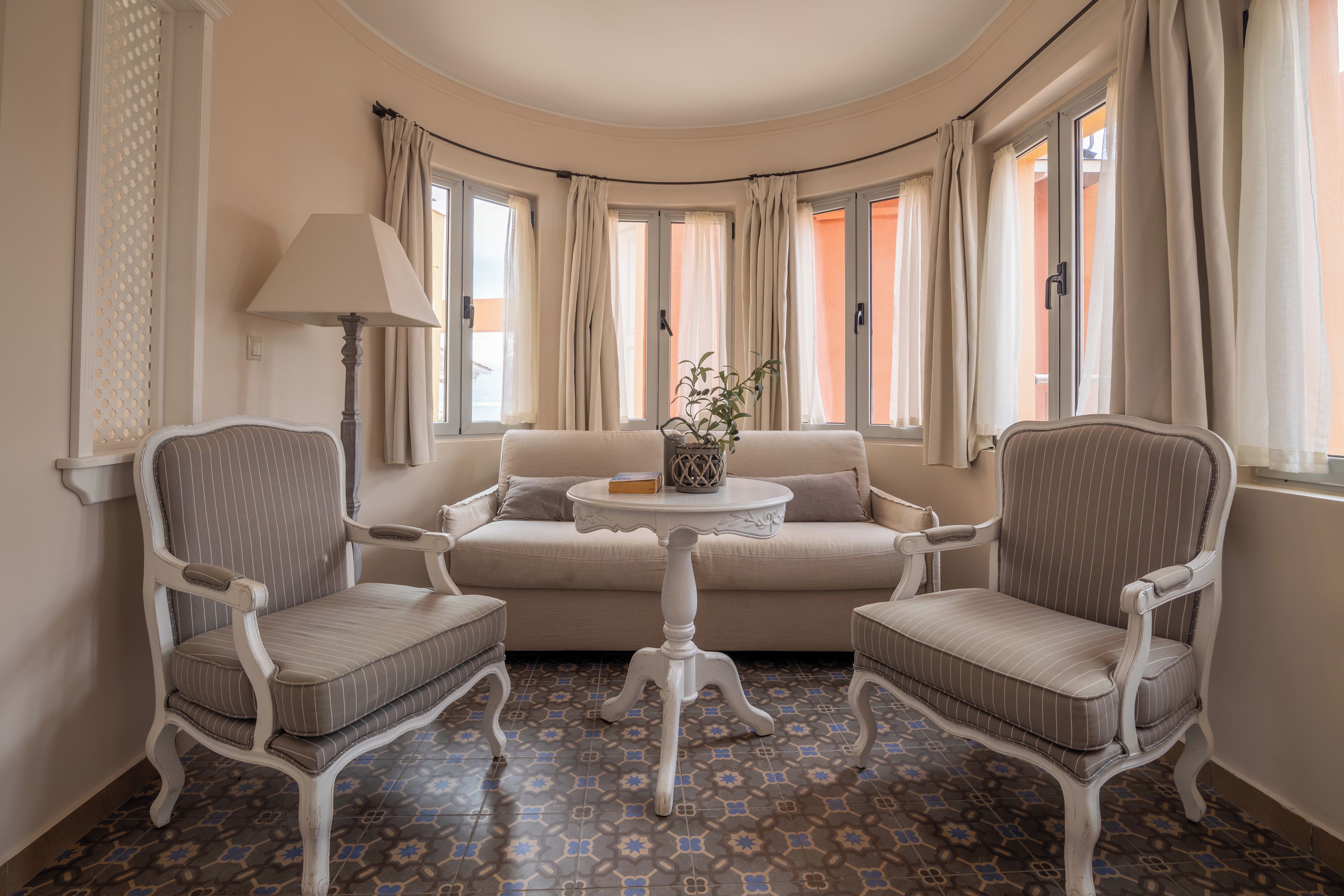 Une pièce comprenant un canapé, deux fauteuils, une petite table ronde et une lampe.