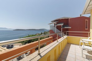 A balcony with a view of the sea, a yellow wall, and a white table and chair. - Red Tower (Lefkada)