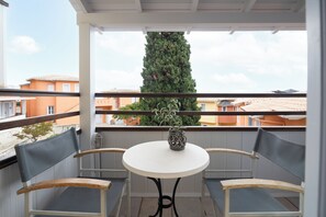 A balcony with two chairs, a small table, and a potted plant. - Red Tower (Lefkada)