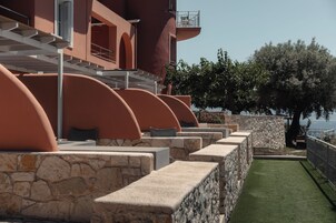 Un hotel frente al mar con zonas de estar al aire libre, paredes de piedra y vistas al océano.