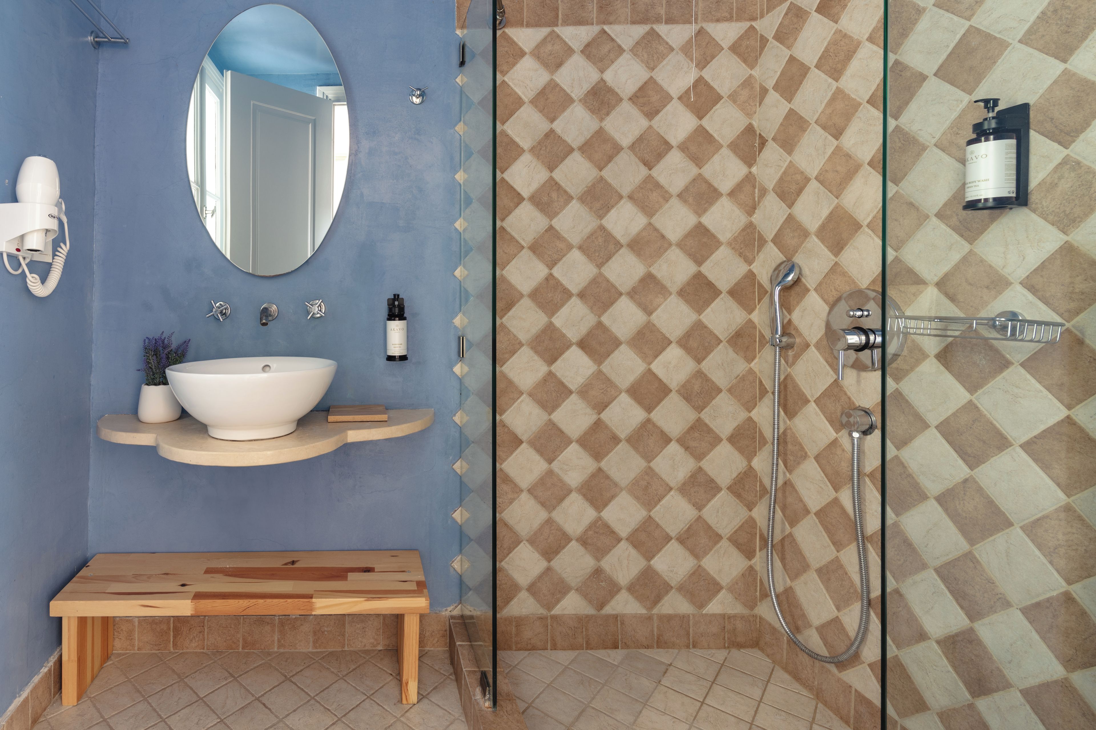 Un bagno con parete blu, lavandino bianco, specchio e doccia con rivestimento a mosaico.