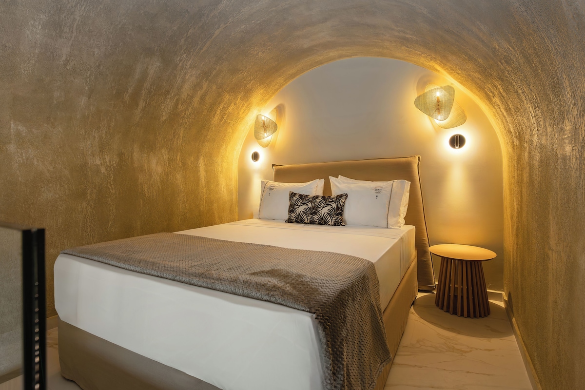 A bedroom with a bed, a bedside table, and a wall-mounted lamp.
