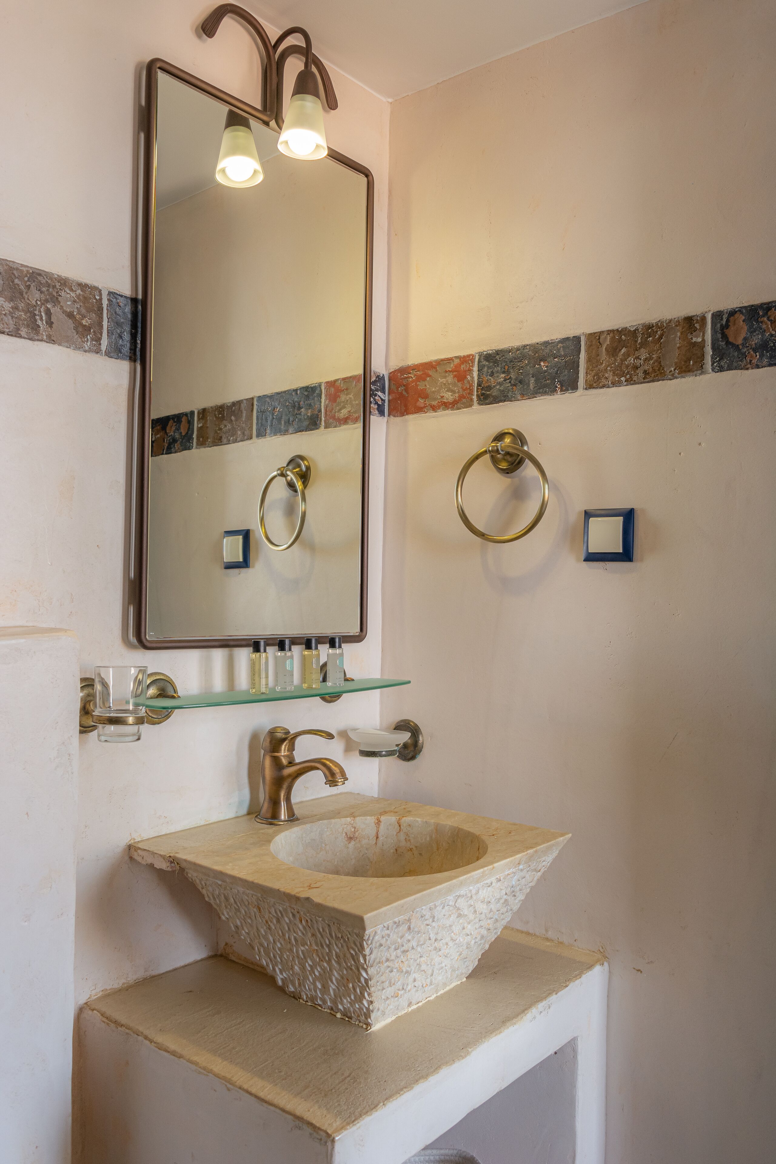 Une salle de bain avec un lavabo en pierre, un grand miroir et deux porte-serviettes.
