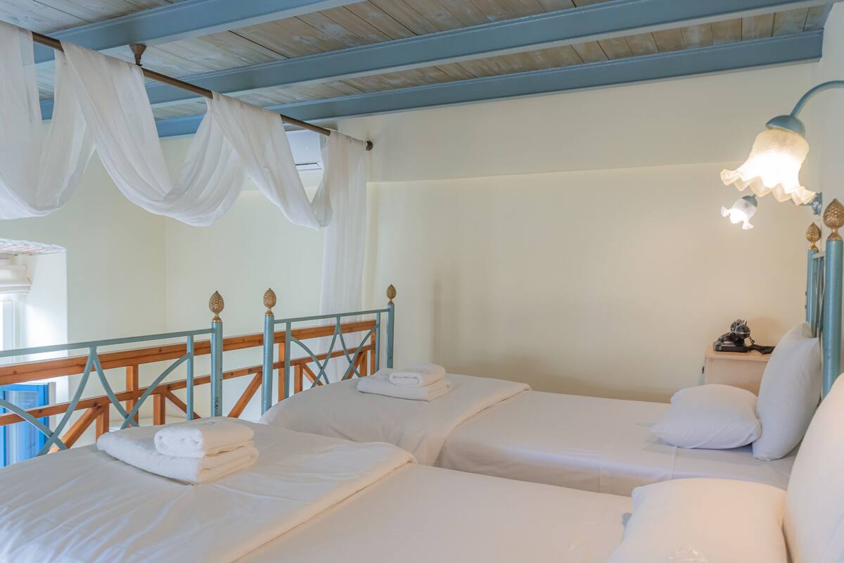 A room with two beds, a wooden headboard, a nightstand, and a hanging lamp.