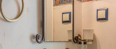 A bathroom with a stone sink, glass shelf, and a mirror.