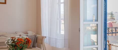 Una habitación acogedora con un sofá color beige, un jarrón de flores y vistas a un balcón con mobiliario exterior.