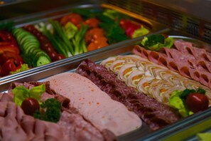 A buffet with various meats, cheeses, and vegetables. - Belarus Hotel (Minsk)