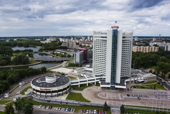 A modern hotel with a central round building and a tall rectangular building with a flag on top. - Belarus Hotel (Minsk)