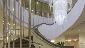 Una escalera curva con barandilla de metal y un candelabro.