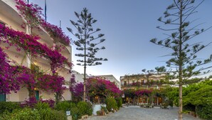 Une cour dallée de pierres, entourée d’une végétation luxuriante et de plantes en fleurs.