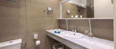 A modern bathroom with two sinks, a large mirror, and a toilet.