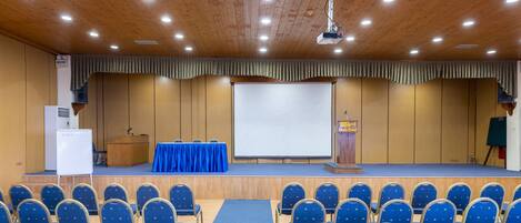Une salle de conférence équipée d’une scène, d’un tableau blanc et d’un pupitre.