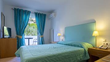 Una habitación de hotel con una cama, un escritorio, una silla, una lámpara y un equipo de aire acondicionado.