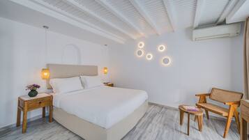 Una habitación de hotel moderna con una cama grande, mesitas de noche, un escritorio y una silla.