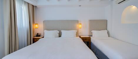 Une chambre d’hôtel avec un grand lit, deux tables de chevet, une petite table et une lampe fixée au mur.