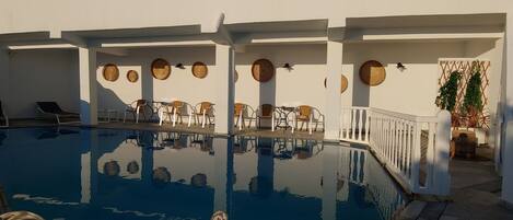 Un área de piscina con sillones reclinables y una piscina cristalina.