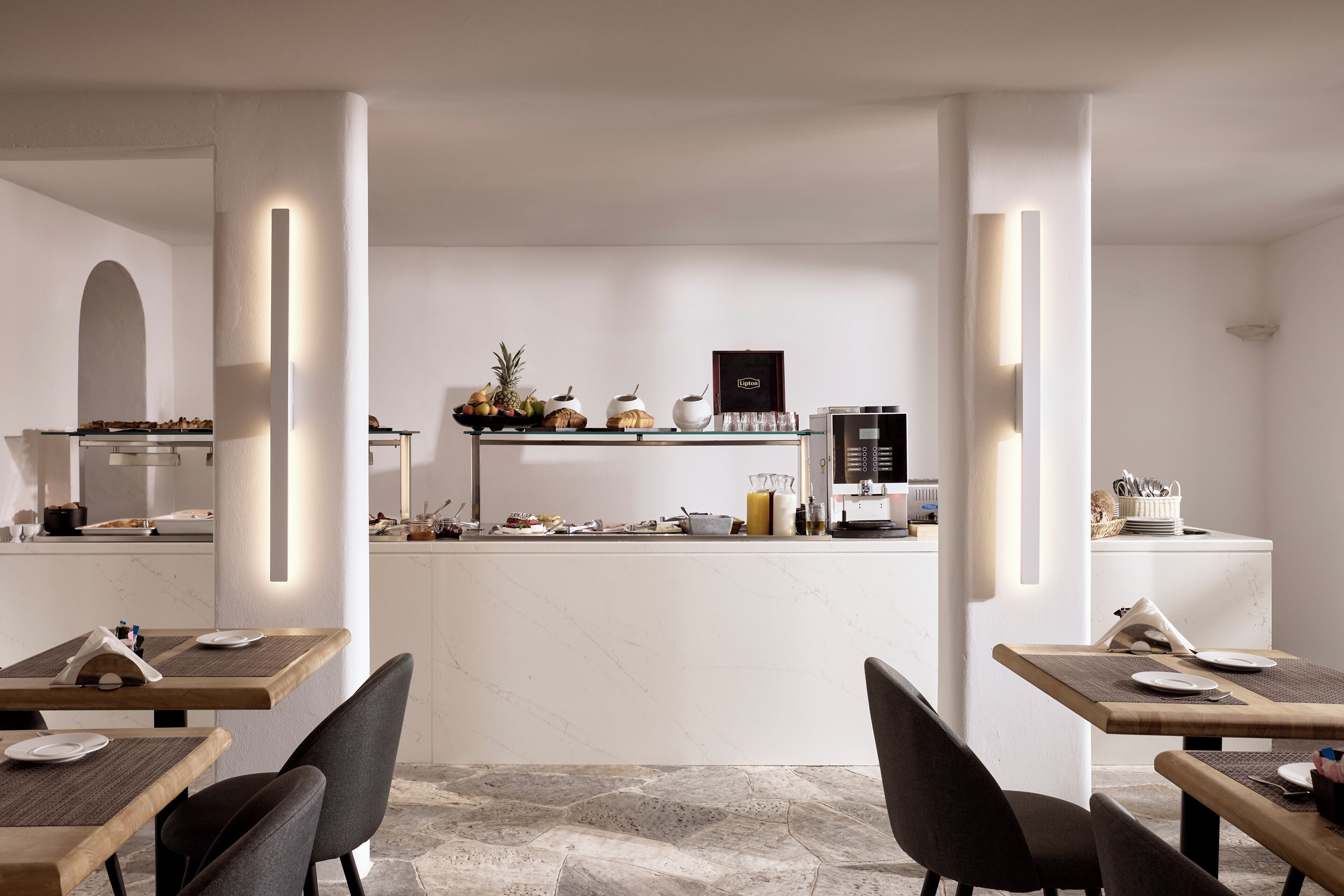 A modern dining area with tables, chairs, and a kitchen in the background.