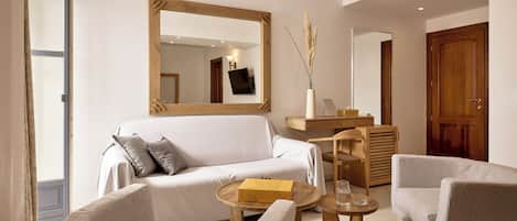 A modern living room with a white sofa, two armchairs, a wooden coffee table, and a large mirror.