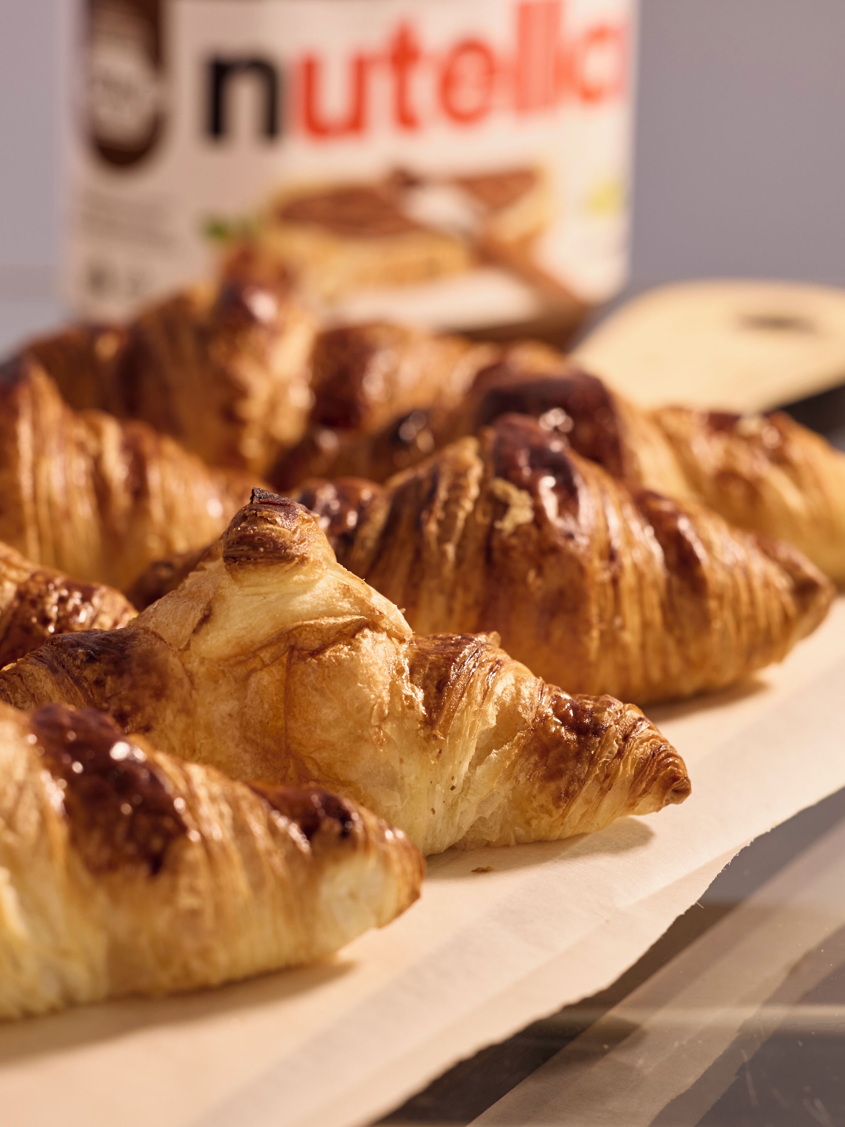 Una bandeja de croissants con un bote de Nutella al fondo.