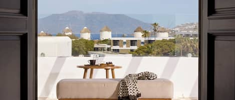 A balcony with a sofa and a table, a view of windmills, and a mountainous landscape.
