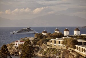 Μια παραθαλάσσια πόλη με ανεμόμυλους, ένα κρουαζιερόπλοιο και παραδοσιακή αρχιτεκτονική.